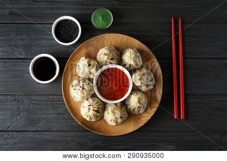 Flat Lay Composition With Plate Of Tasty Baozi Dumplings, Sesame Seeds And Sauces On Wooden Table
