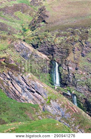 A Waterfall Tumbles Through A Narrow Rocky Gully Among Grassland In The Oa Nature Reserve On The Isl