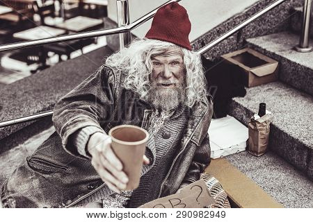 Lonely Mendicant Begging Pedestrians For Money With Paper Cup.