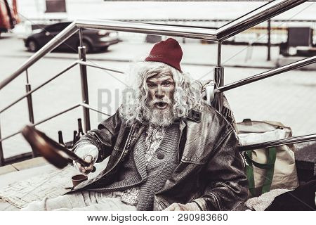 Angry Almsman Sitting And Threatening Strangers With Cane.