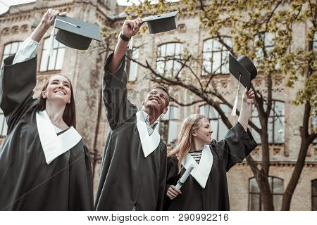 Positive Delighted Leavers Raising Their Graduation Hats