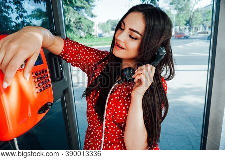 Woman Using Old And Weathered Oldstyle Plublic Pay Phone In Phone Booth.