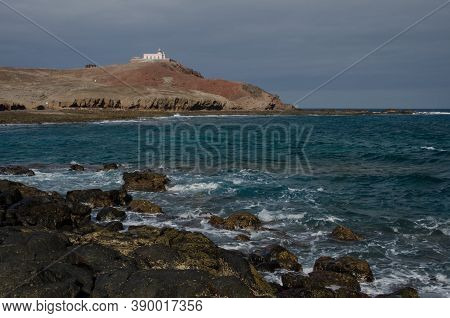 Coastal Landscape And Arinaga Lighthouse In The Background.