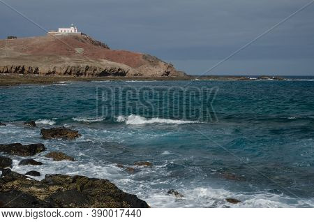 Coastal Landscape And Arinaga Lighthouse In The Background.