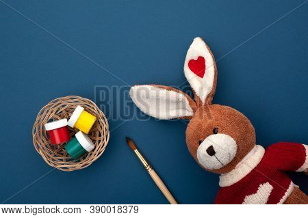 Paints Are In A Basket, Next To An Artist's Brush And A Plush Rabbit