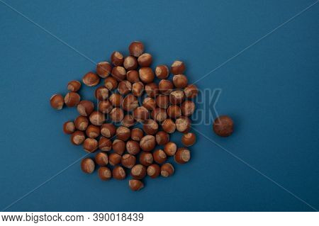 Hazelnuts Lie In A Heap On A Blue Background, Next To Macadamia