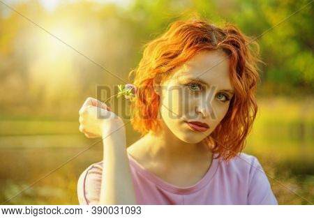 Ginger Woman Wearing A Dress With Clover Flower In Autumn Park. Shallow Dof