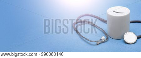 Cost Of Healthcare. Money Box With A Medical Doctors Stethoscope On Blue Background. Place For Text.