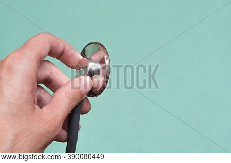 Female Hand Holds A Stethoscope On A Blue Background. Concept Doctor, Doctors Appointment, Virus, Tr