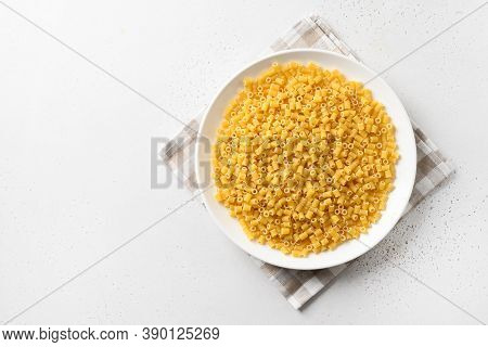 Raw Ditalini Pasta In White Plate On White Background. View From Above. Copy Space.