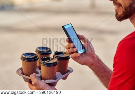 Delivery Man Holding Smartphone And Coffee Cups