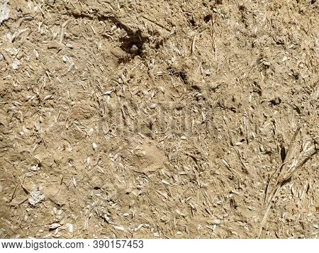Close-up Background Of The Wall Of An Old House Made Of Clay Mixed With Straw. Old Type Of Construct
