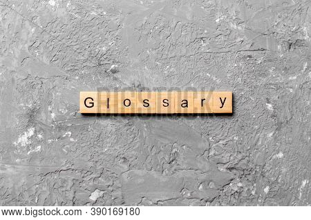 Glossary Word Written On Wood Block. Glossary Text On Cement Table For Your Desing, Top View Concept