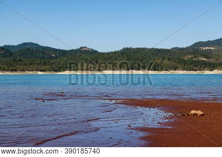 Low Water Levels Reveal Red Clay And Rocks At Lost Creak Lake Near Prospect, Oregon Located In The C