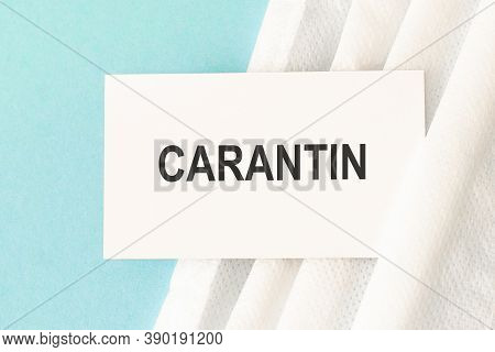 Word Carantin With Medical Mask On A Blue Background.