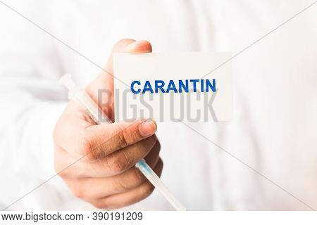 Word Carantin On A White Background With A Syringe In Hand. Medicine Concept