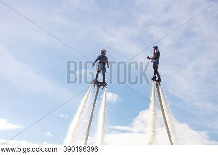 Russia. Vyborg. 05.09.2020. Two Men Fly On A Flyboard Against The Background Of The Sky With Clouds
