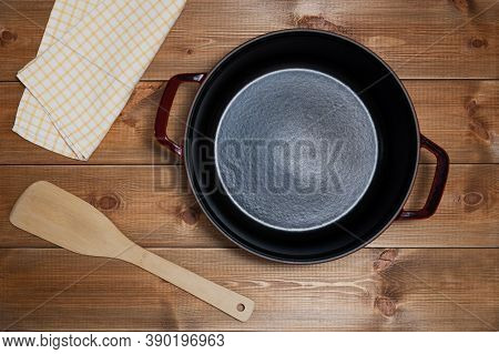 Empty Cast Iron Sause Pan With Nepkin And Spatula On Wooden Table Background, Top View.