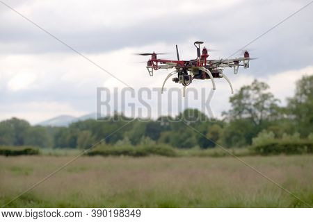 Large Hex Copter Camera Drone Hovers In Front Of A Rural Back Ground Of The Malvern Hills. Autonomou
