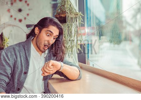 Handsome Man On A Date, His Girlfriend Being Late, He Looks To Wristwatch For Time, Sitting In A Cof
