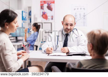 Mature Woman With Walking Disablity In Wheelchair With Daughter During Medical Check With Doctor In 