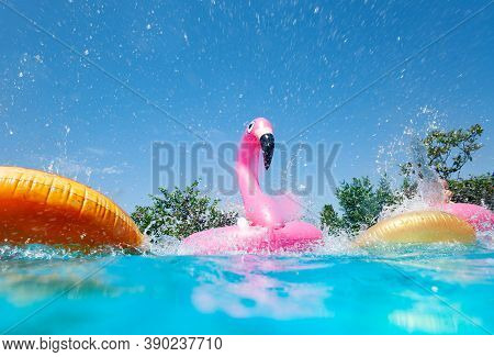 Funny Action Photo In The Outdoor Swimming Pool With Splashes Of Inflatable Flamingo And Doughnuts B