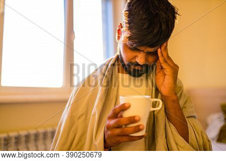 Arabian Indian Man Drinking Hot Lemon Dinder Masala Tea In Morning Bedroom While Feeling Cold Covere