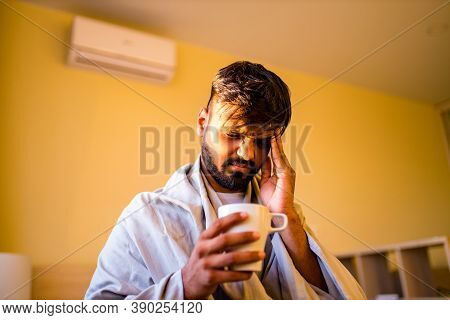 Arabian Indian Man Drinking Hot Lemon Dinder Masala Tea In Morning Bedroom While Feeling Cold Covere