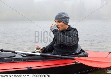 Breakfast In Canoe In Middle Of River, Man Enjoying Hot Beverage From Thermos, Guy Wearing Warm Blac
