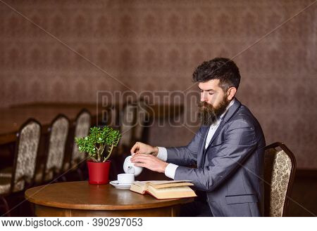 Senior Man Reading Book With Tea At Home