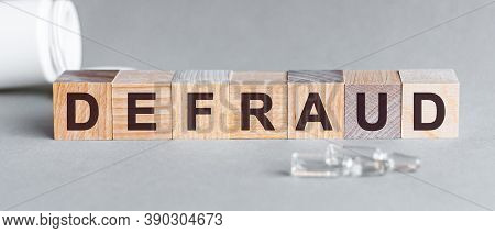 Defraud Is A Word Written In Black Letters On Wooden Cubes.