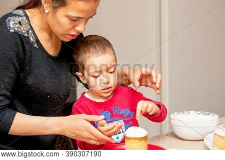 Mom Teaches Young Son To Decorate Easter Cake With Multi-colored Jewelry