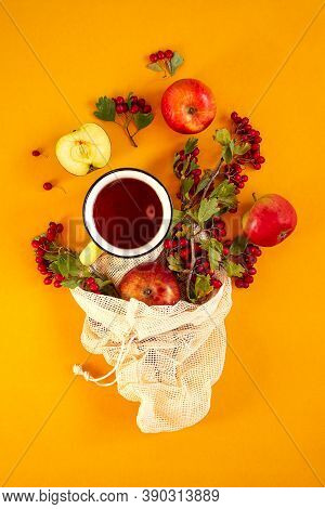 Red Garden Organic Apples, Hawthorn Berries In A Mesh Bag And Cup Of Hot Tea On An Orange Background