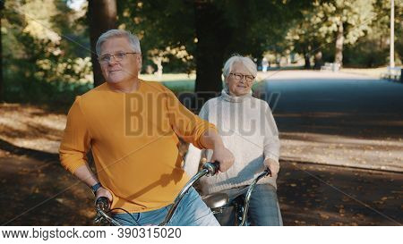 Senior Couple Riding Double Bicycle In Autumn. Grandmother And Grandfather Cycling Together . Elderl