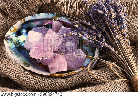 A Top View Image Of Rose Quartz Healing Crystal In An Abalone Shell With Dried Lavender Flowers.