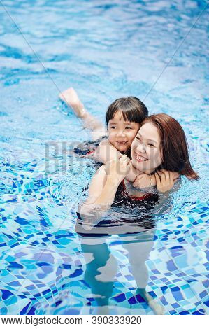 Scared Little Girl Hugging Mother As She Is Afraid Of Swimming In Pool