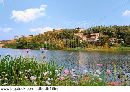 The idyllic mountain tranditional Chinese village by river on a beautiful summer afteroon with blossoming trees and flowers in the south of China