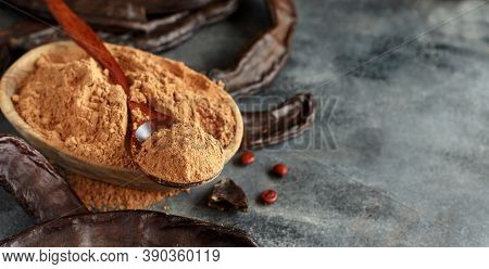 Dry Carob Pods And Powder Close Up On A Grey Table