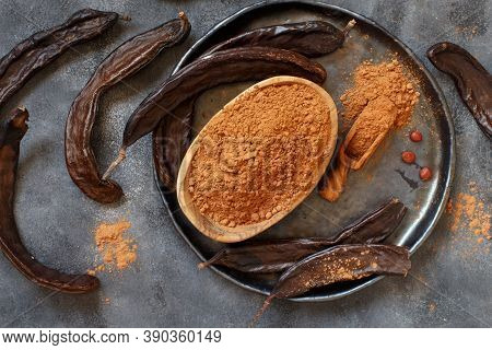 Dry Carob Pods And Powder Top View On A Grey Table