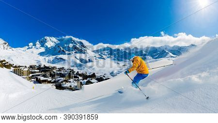 Ski in winter season, mountains and ski touring man on the top in sunny day in France, Alps above the clouds.