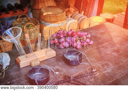 Professional Winemaking, Table With Grapes And Flasks For Sampling. Barrels For Wine, Bottles And Gr
