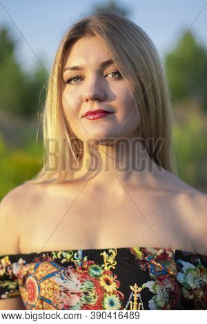 Overlight Bright Portrait Of A Charming Attractive Blonde In Flowery Dress In The Field