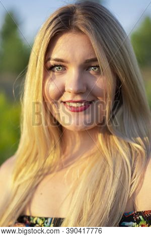 Overlight Bright Portrait Of A Charming Attractive Blonde In Flowery Dress In The Field