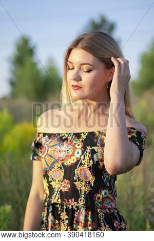 Overlight Bright Portrait Of A Charming Attractive Blonde In Flowery Dress In The Field