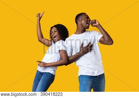 Emotional Black Man And Woman Dancing And Singing On Yellow Studio Background With Copy Space. Joyfu