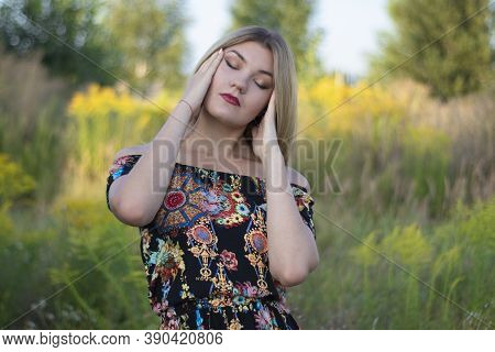 Overlight Bright Portrait Of A Charming Attractive Blonde In Flowery Dress In The Field