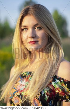Overlight Bright Portrait Of A Charming Attractive Blonde In Flowery Dress In The Field