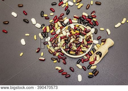 Mix Of Various Dry Legumes In Ceramic Bowl, Scattered On Black Stone Background