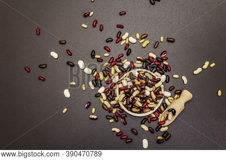 Mix Of Various Dry Legumes In Ceramic Bowl, Scattered On Black Stone Background