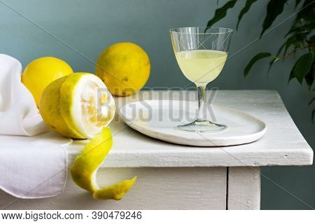 Italian Liqueur Limoncello In Crystal Glasses And Ripe Lemons On A Wooden Table.